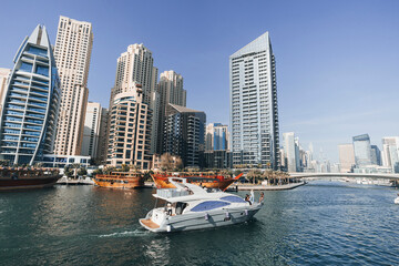 Fototapeta na wymiar luxury yachts take tourists on the water in the bay near the coast of Dubai Dubai Marina in summer day, United Arab Emirates. In city of artificial channel length of 3 kilometers along Persian Gulf