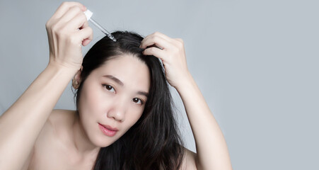 Asian beautiful woman drop serum on hair to enrich and prevent hair loss and grey hair