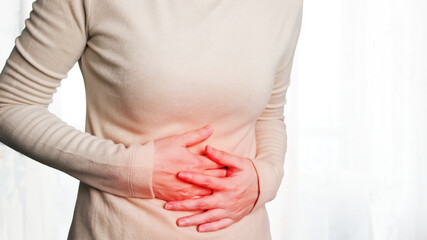 Woman uses hand hold on stomach because indigestion, painful illness, menstruation and eating...