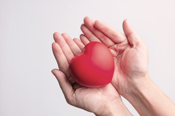 Red heart shape is in hands to give love and care as gift on valentine's day. Symbol of love.