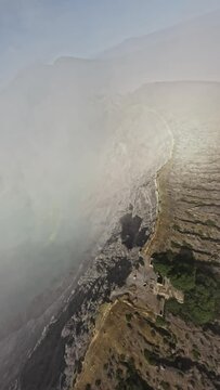 FPV sport drone dive shot tropical island volcano ridge smoke panorama stone crater mist gas steam landscape aerial view. Cinematic exotic scenery volcanic acid lake mountain travel. Vertical video 4k