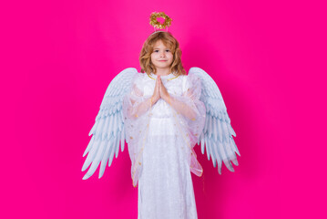 Angel prayer. Child at angel costume with prayer hands, hope and pray concept. Kid with angel wings. Isolated studio shot.