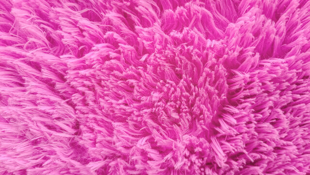 Close-up of a pink furry rug. pink background