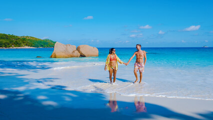 Praslin Seychelles tropical island with white beaches and palm trees, a couple of men and women mid age on vacation at Seychelles visiting the tropical beach of Anse Lazio Praslin Seychelles.