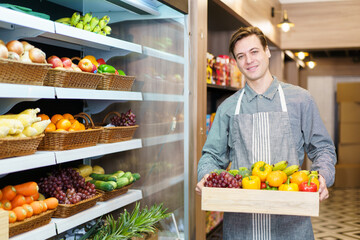 Happy cheerful caucasian grocery store staff arranging a vegetables and fruits on the shelf. Woman staff are working in food and vegetable hypermarket or grocery store.