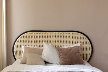 Cozy rattan oval round headboard with pillows in white beige sand and natural brown. Comfortable...