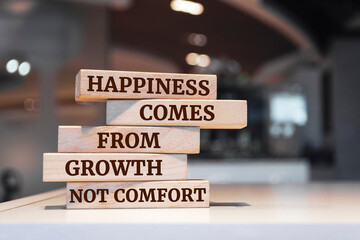 Wooden blocks with words 'Happiness comes from growth, not comfort'.