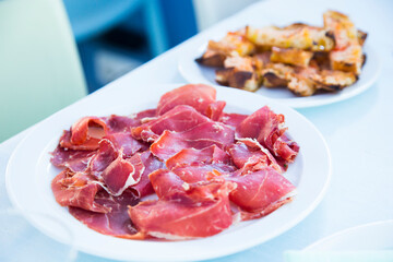Iberico ham cut into slices. Iberian ham is a type of serrano ham from the Iberian pig, highly regarded in Spanish gastronomy
