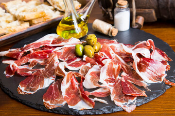 Iberico ham cut into slices. Iberian ham is a type of serrano ham from the Iberian pig, highly...