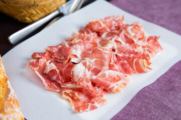 Iberico ham cut into slices. Iberian ham is a type of serrano ham from the Iberian pig, highly regarded in Spanish gastronomy