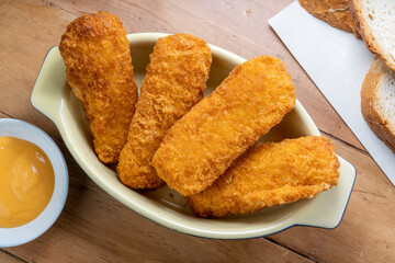 Fish fingers or fish sticks grilled, shallow deep-fried in dish on Table background ready to eat.