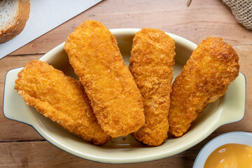 Fish fingers or fish sticks grilled, shallow deep-fried in dish on Table background ready to eat.