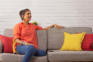 Happy young woman watching TV in living room