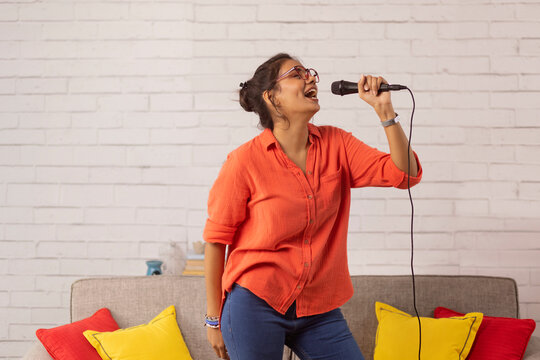 Portrait of a young woman singing in living room at home