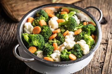 Steamed broccoli, carrots and cauliflower in a stainless steel steamer. Healthy vegetable concept