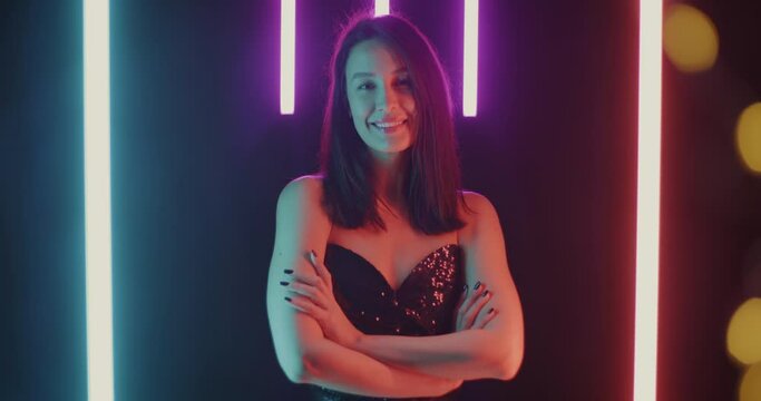 Slow motion portrait of cheerful woman crossing eyes and looking at camera with smiling face on beautiful neon background. Positive emotion and nightlife concept.