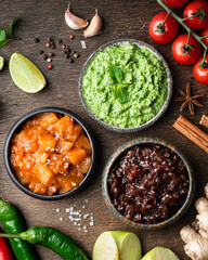 Set of indian chutneys with ingredients on wooden background, top view
