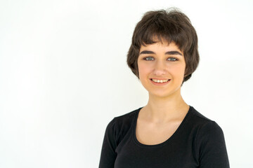 Portrait charming young woman in black clothes smiling broadly with white teeth and looking at the camera, over gray background. Caucasian girl glows with happiness