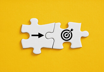 Goal target and arrow symbols connected on jigsaw puzzle pieces.