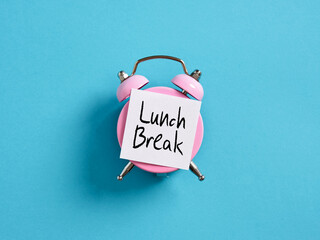 Lunch break time reminder or notice message. Pink alarm clock with a note paper on blue background...