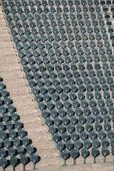 Obraz premium Empty rows of new comfortable plastic chairs attached to floor in an empty stadium. Seat designed for sports arenas. Stone staircase of sports stadium divides chairs into sectors.