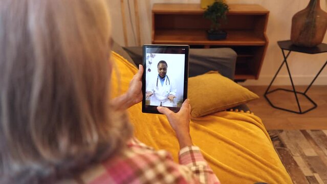 old woman talks with doctor by video call from home