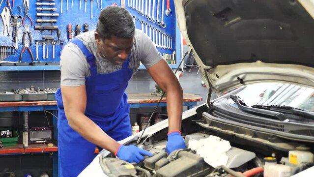 Skilled car mechanician changing filter in vehicle in the auto repair shop