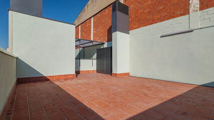 An empty spacious terrace on a roof of a large house with tiled red floor for relaxing on warm summer evenings in the sun of the passing day. Sunlight illuminates the roof.