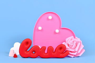 Valentine's Day decoration with red word love, roses and heart ornaments on blue background