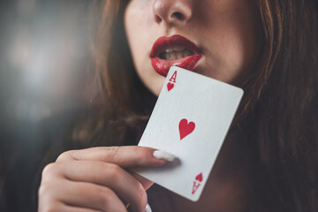 Casino woman with red lips holding ace with seductive lips and teeth. face close up