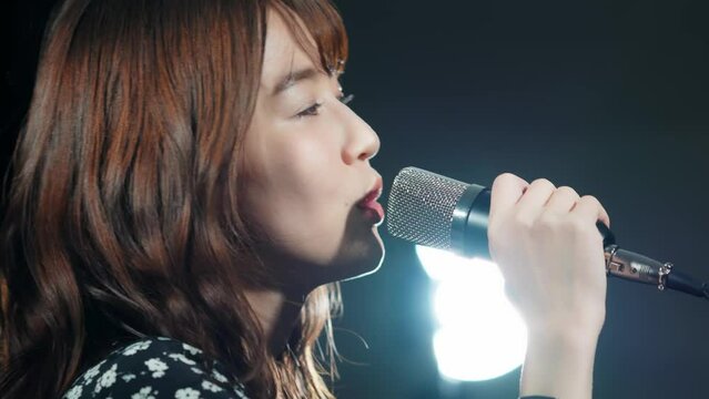 スポットライトを浴びて歌う女性　ライブ　コンサート　カラオケ