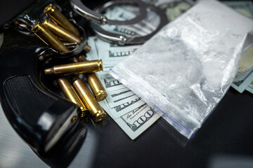 Plastic bags of cocaine or heroin and US dollar bills with handcuffs and bullets from a gun.