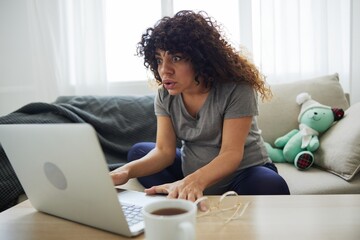 A pregnant woman smile sits at home on the sofa with a laptop and watches tv shows movies and series. Lifestyle of a pregnant woman, preparation for childbirth, last month of pregnancy