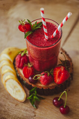 From above view of glass with fresh crimson smoothie with banana and berries on wooden table. 