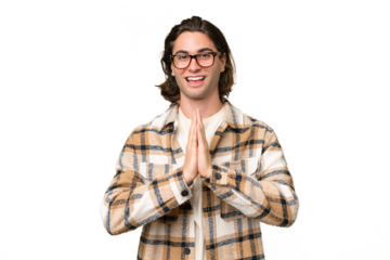 Young caucasian man isolated on green chroma background keeps palm together. Person asks for something