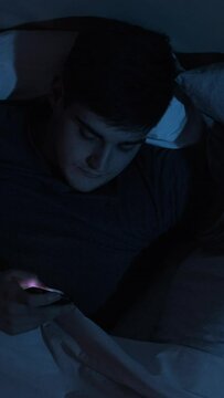 Mobile cheating. Internet affair. Infidelity betrayal. Disloyal sneaky husband using phone for secret chat lying in bed with sleeping wife late at night. Vertical video.