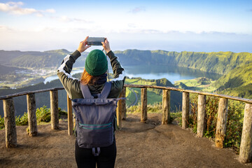 Young woman taking a picture of the scenic views of São Miguel island in the Azores	
