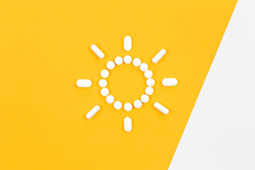 Pills in the shape of the sun, on a yellow background, flat lay.