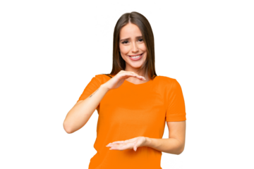 Young pretty caucasian woman over isolated background holding copyspace imaginary on the palm to insert an ad