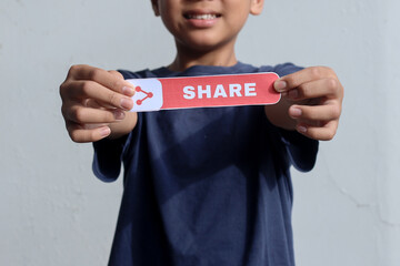 Young blogger boy showing printed paper with Share text, asking people to share his video. Blogging, technology.