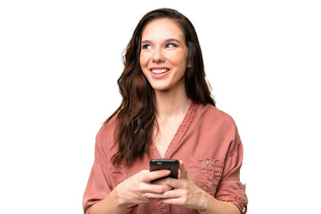 Young caucasian woman over isolated background using mobile phone and looking up