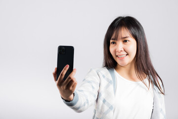 Fototapeta premium Woman excited holding smartphone to shooting selfie photo front camera studio shot isolated white background, happy young female smiling taking photography by mobile phone on mobile phone