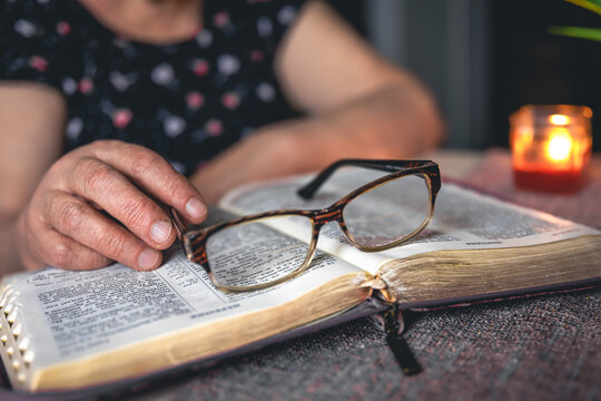 An old woman reads the Bible, hands close up.