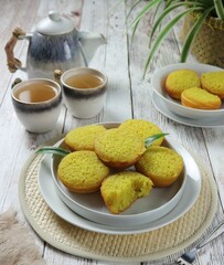 Indonesian typical kue bika cake served on a white plate against a cup and teapot background
