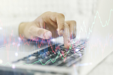 Multi exposure of abstract financial graph with hand typing on laptop on background, financial and trading concept