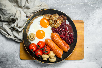 English breakfast. Fried eggs with sausages, bacon and beans.