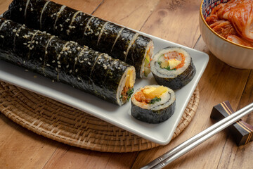 California Maki in white plate on wooden table, Steamed rice wrapped in seaweed with shrimp eggs meat and vegetable.