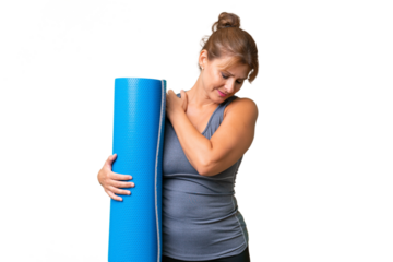 Middle-aged sport woman going to yoga classes while holding a mat over isolated background suffering from pain in shoulder for having made an effort