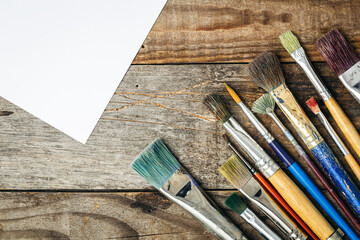 Fototapeta premium Paint brushes of different sizes on a wooden background, flat lay.