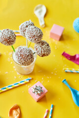 Festival birthday background with delicious homemade popcake coconut chocolate cake pops on a yellow background, festival desserts, tasty food